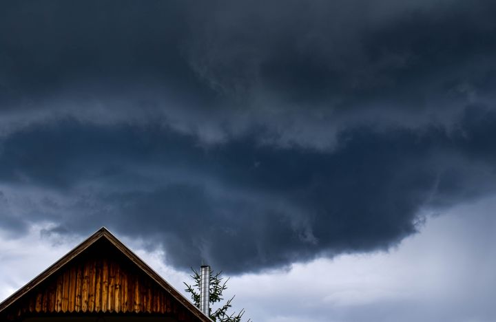 Tummia myrskypilviä puisella rakennuksella.