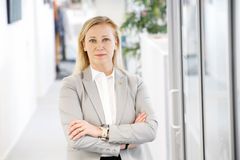 Kuvassa on Katarina Murto vaaleassa bleiserissä, seisoo käytävällä kädet ristittynä.