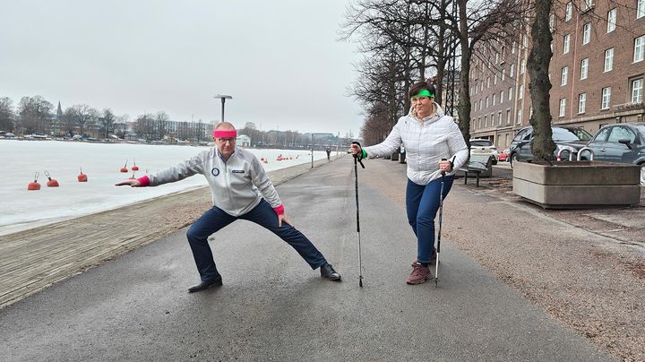 Jarkko Eloranta ja Katja Syvärinen verryttelevät jalkakäytävällä hikipannat päässään, Katjalla lisäksi kävelysauvat.