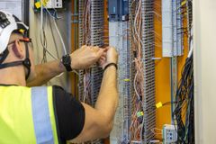 Henkilö työskentelee sähkökaapin kytkentöjen parissa.