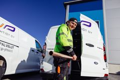 Mies hymyilee pitäessään putkea kädessään kahden JP Yhtiöiden logolla varustetun pakettiauton edessä.
