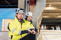 Kaksi henkilöä keltaisissa turvatakeissa ja kypärissä LUMI-supertietokoneella.