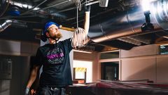 Mies työskentelee rakennustyömaalla LVIS-asennuksen parissa kypärä päässä.