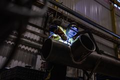Hitsaaja työskentelee ison metalliputken parissa teollisuusympäristössä.