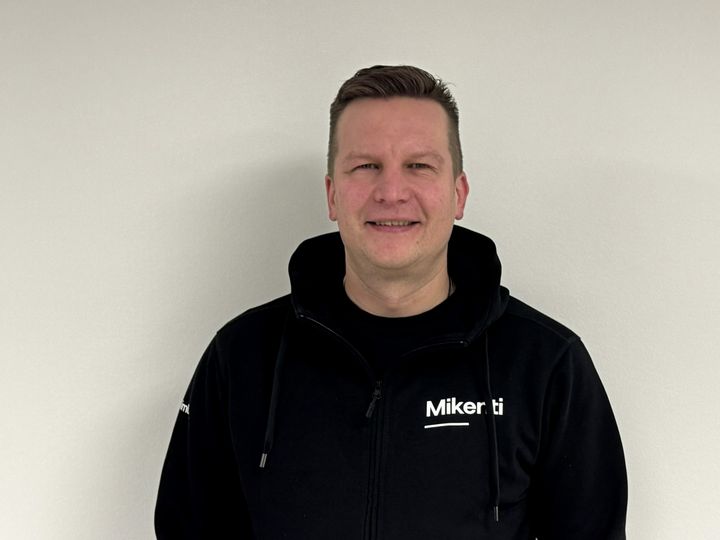 Mikko Oksanen, Mikentin tuleva toimitusjohtaja, hymyilee kameralle mustassa Mikenti-logolla varustetussa hupparissa.