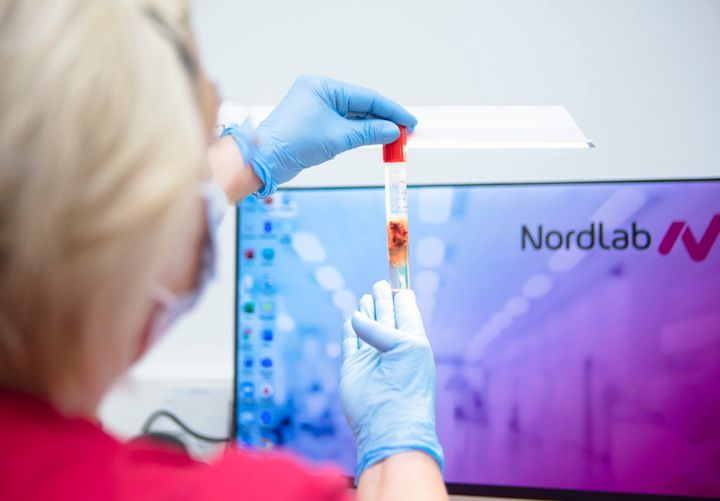 Työntekijä tarkistaa laboratorionäytettä tietokoneen ruudun edessä