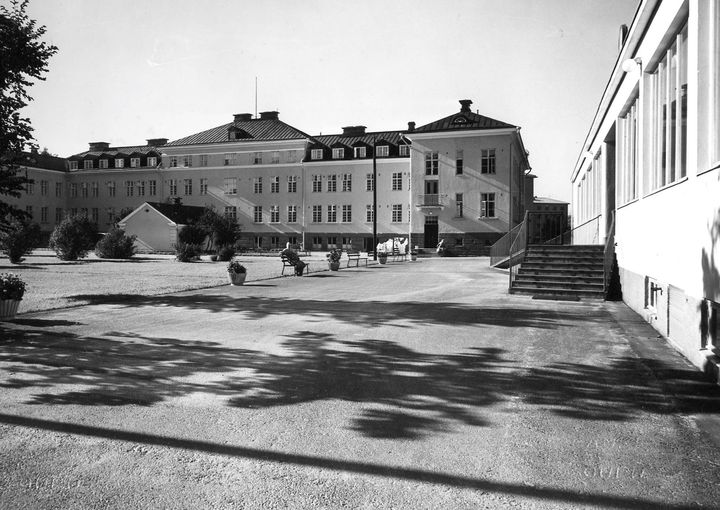 Vanha, iso rakennus mustavalkoisena. Etualalla myös pihapiiriä.