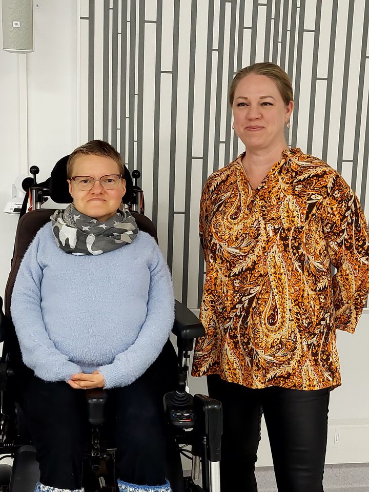 Kaksi naista. Vasemmanpuoleinen istuu pyörätuolissa.