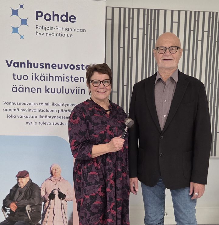 Mies ja nainen. Naisella puheenjohtajan nuija kädessä.