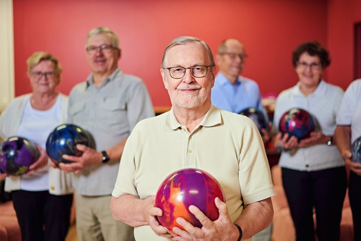 Ikäihmisiä keilapallo kädessä.