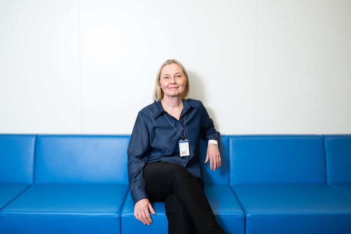 Katri Korolainen istuu sinisellä sohvalla.