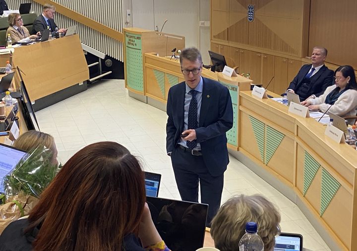 Hyvinvointialueen johtaja Ilkka Luoma seisoo aluevaltuuston edessä ja puhuu valtuutetuille.