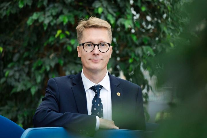 Mies%20katsoo%20kameraan%20ja%20hymyilee.