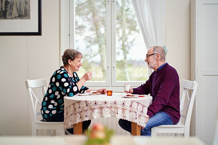 Kaksi ikäihmistä kahvipöydän ääressä.