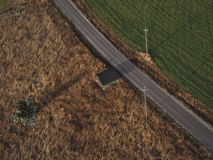 Ilmakuva sähkölinjasta pellon ja tien vieressä Järvi-Suomessa.