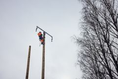 Asentaja työskentelemässä korkealla sähköpylväässä talvisessa maisemassa.