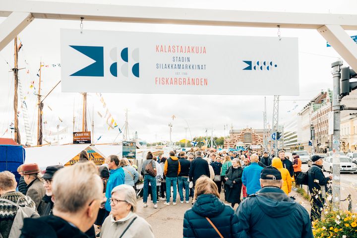 Kuvassa Stadin Silakkamarkkina-alueen portti ja ihmisiä markkinoilla.