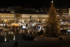Kuvassa Senaatintorin iltahämärässä kuvattuna Tuomiokirkon portailta. Tuomaan Markkinoiden valot loistavat myyntimökeissä ja juolukuusessa.