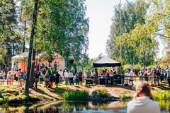 Ulkoilmakonsertti metsäisessä ympäristössä, jossa yleisö nauttii live-musiikista.