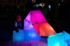 Lapsi tutkii värikkäitä ja valaistuja geometrisia paloja pimeässä ulkotilassa.