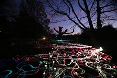 Värikkäät valokuitunauhat kulkevat pimeässä maisemassa, loistaen ja sykähdellen eri värisinä, luoden animoidun vaikutelman.