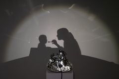 Varjo heijastaa äidin ruokkimassa lasta Hietalahden kauppahallin seinälle.