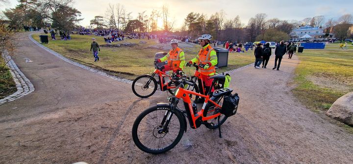 Kaksi ensihoitajaa sähköpolkupyörien kanssa puistossa