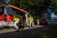 Pelastushenkilöstöä astumassa ulos ambulanssista puistomaisemassa.