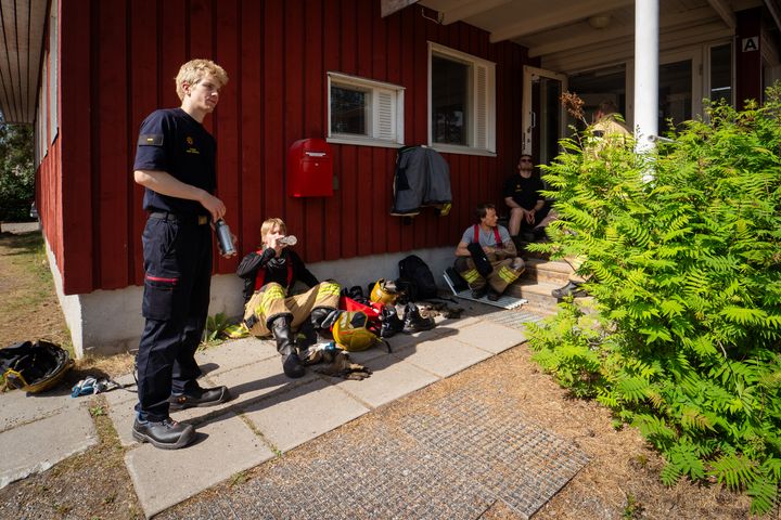 Palomiehet istuvat varjossa tauolla juomassa vettä.