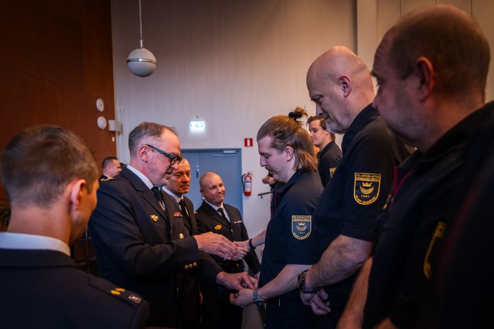 Palomiehiä juhlapuvuissa auditoriossa.