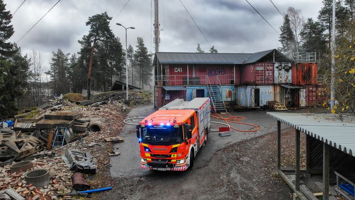 Pelastusyksikkö harjoitusalueella, jossa on useita kontteja ja raunioita ympäriinsä.