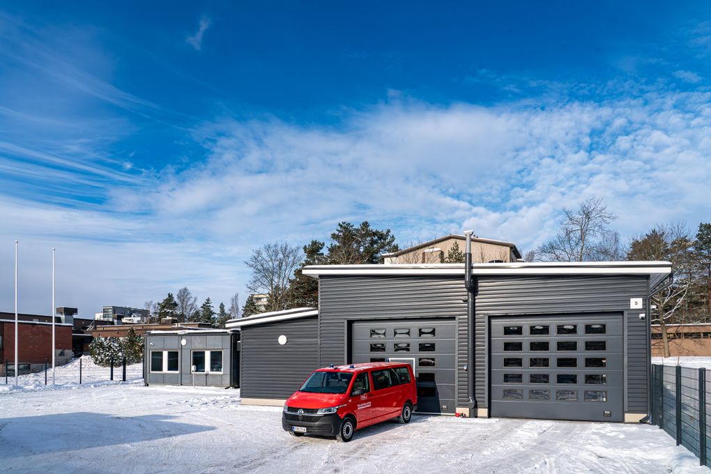 Punainen paloauto pelastusaseman edessä lumisessa maisemassa.