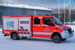 Punainen pelastusajoneuvo parkkeerattuna lumisella alueella.