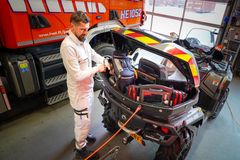 Palomies varustelee pelastusasemalla mönkijää, jonka takalaatikko on auki. Taustalla näkyy pelastusajoneuvo.