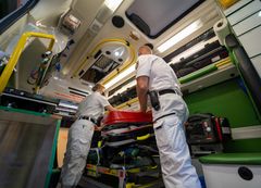 Ambulanssin ensiapuhenkilöstö työskentelee ajoneuvon sisällä.