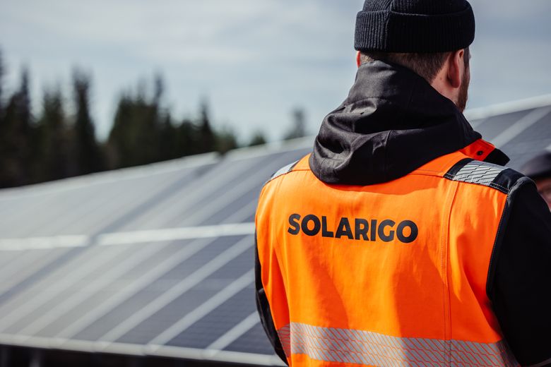 Solarigo Systems Oy:n työntekijä juttelemassa aurinkopaneelien läheisyydessä kansalaisen kanssa.