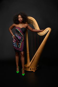Kuvassa Brandee Younger nojaa kultareunaiseen harppuun olkaimeton iltapuku päällä.