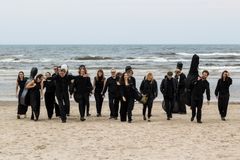 Kremerata Baltica -kamariorkesteri kävelee rannalla, taustalla merta.