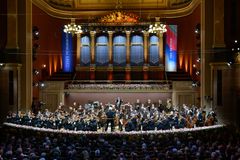 Orkesteri soittaa lavalla konserttisalissa, yleisö seuraa esitystä.