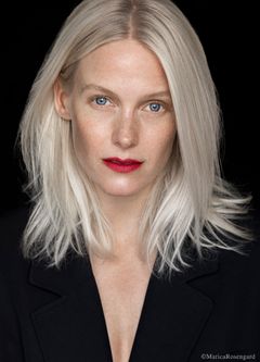 Laura Birn mustassa asussa, katsoo suoraan kameraan mustan taustan edessä.