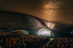 Konsertti Huvilassa: suuri katos, lavalla esiintyjiä ja yleisö istumassa.