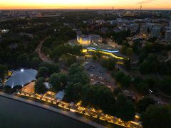 Ilmakuva iltahämärässä, jossa valaistu Huvilaranta-terassialue näkyy puiden ympäröimänä kaupungin keskustan läheisyydessä.