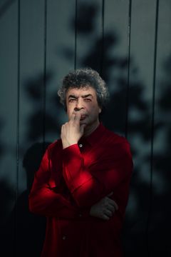 Kuvassa Semjon Bytškov punaisessa paidassa, käsi leualla nojaa harmaaseen lautaseinään, johon heijastuu varjoja.