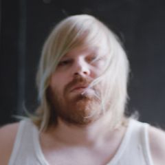 Kuvassa Hannes, jolla on vaalea, pitkä tukka ja parta. Hän katsoo suoraan kameraan.