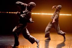 Kaksi tanssijaa esiintyy intensiivisesti lavalla, värivalot loistavat taustalla.