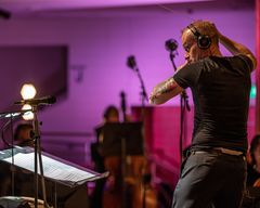Conor Mitchell ohjaamassa orkesteria salissa, jossa on värikkäitä valoja.