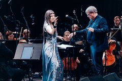 Esiintymiskuva konsertista, jossa laulaja Katarina Barruk laulaa ja kapellimestari johtaa orkesteria.