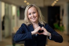 Nainen muodostaa käsillään sydämen.