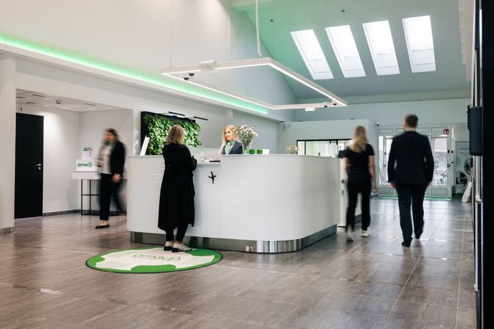 Pankkikonttorista näkymä, keskellä valkoinen infotiski, jonka ympärillä asioivia.