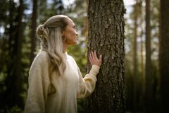 Kuvassa nainen metsässä koskettamassa puuta